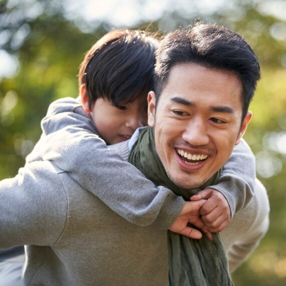 Asian,Father,Carrying,Son,On,Back,Having,Fun,Outdoors,In