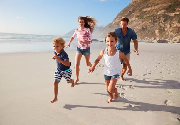 Parents,Running,Along,Beach,With,Children,On,Summer,Vacation
